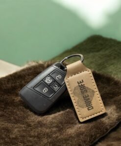 Tan vegan leatherette keychain engraved with Drive Safe beside a car key fob