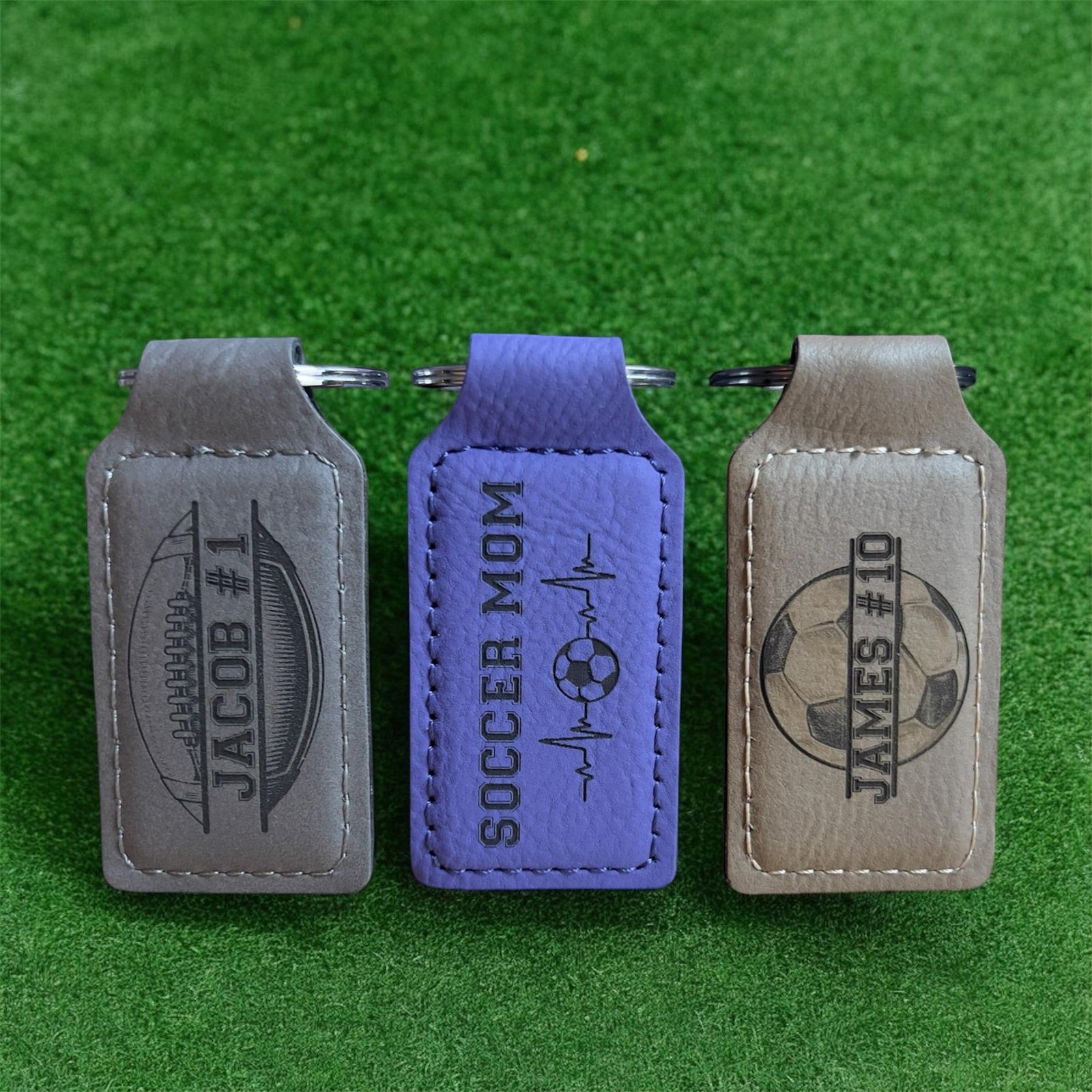 Three engraved vegan leatherette keychains in gray, purple and tan colors