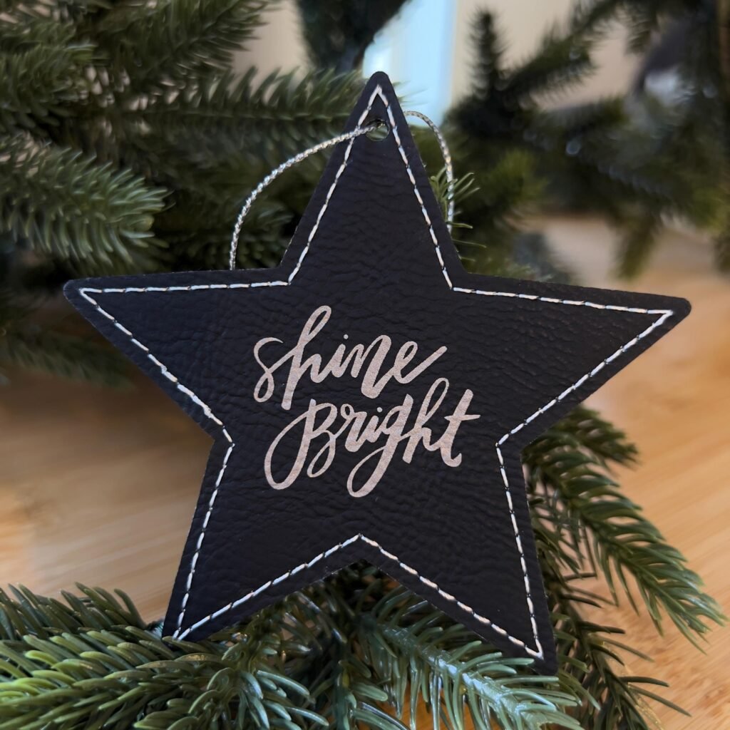 Engraved Christmas ornaments for companies: black leatherette star ornament with Shine Bright script engraved in silver