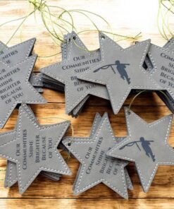 Gray leatherette star Christmas ornaments with gold cords engraved with Our Communities Shine Brighter