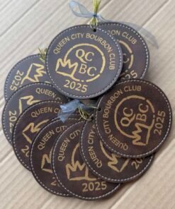 Dark brown round leatherette Christmas ornaments engraved with a sample bourbon club logo and 2025